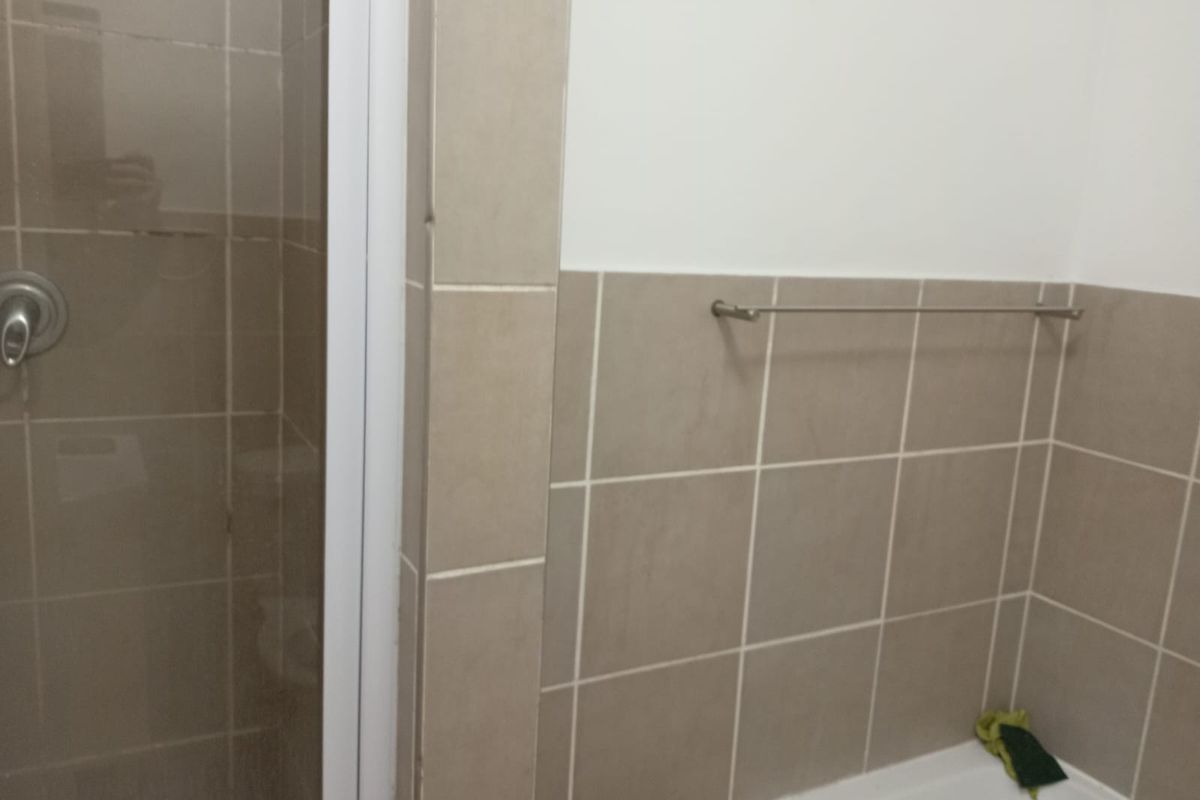 A functional bathroom featuring a shower enclosure with tiled walls and a wall-mounted towel rail.