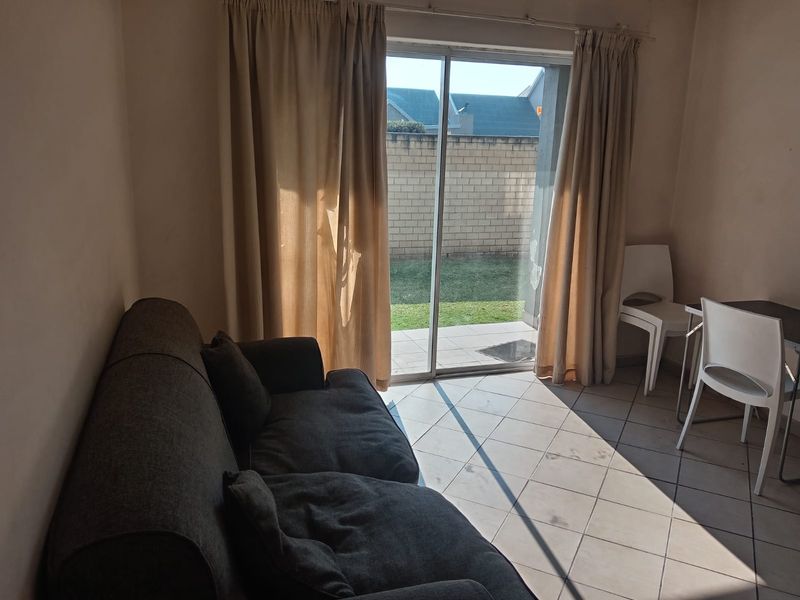 A living area featuring ceramic floor tiles and a sliding glass door providing direct access to the rear patio and garden.