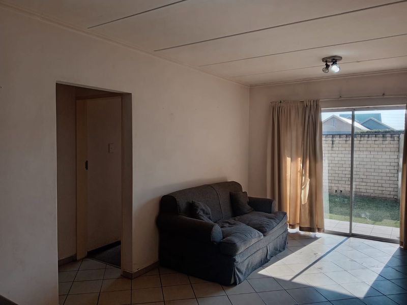 A living room featuring tiled flooring and a sliding glass door providing access to the rear garden area.