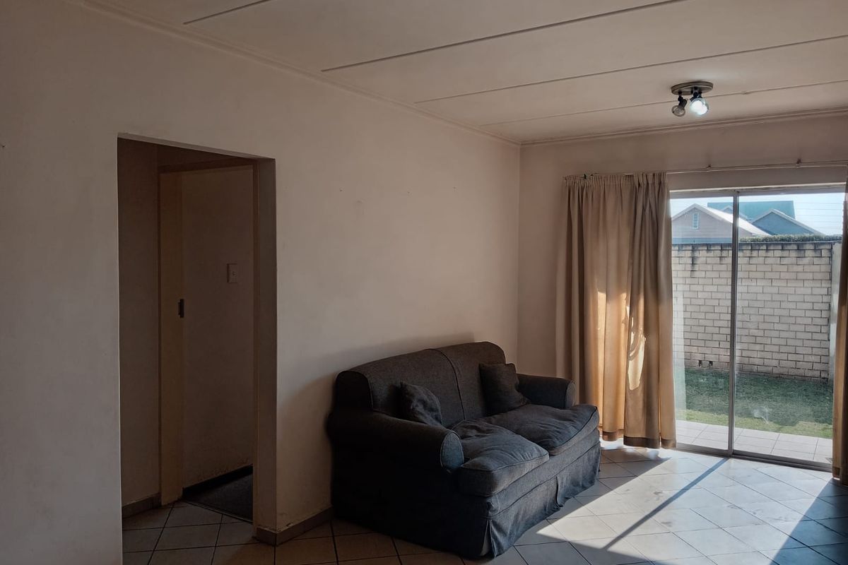 A living room featuring tiled flooring and a sliding glass door providing access to the rear garden area.