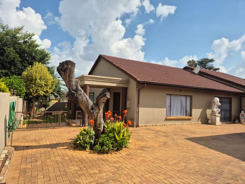 A well-maintained single-story home featuring a paved driveway, tiled roof, and a covered entrance area with established garden landscaping.