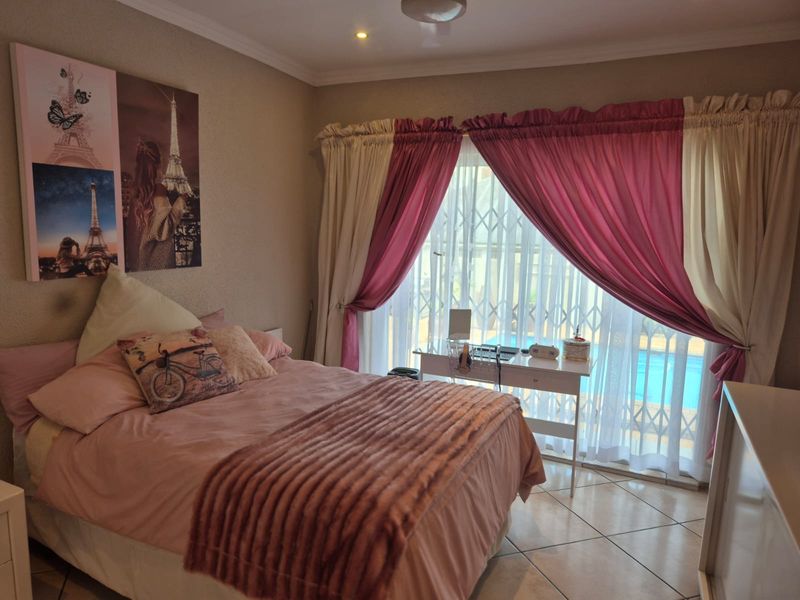 A bedroom featuring tiled flooring, recessed lighting, and a sliding door with a security gate leading to an outdoor area.