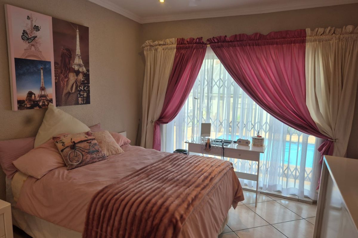 A bedroom featuring tiled flooring, recessed lighting, and a sliding door with a security gate leading to an outdoor area.
