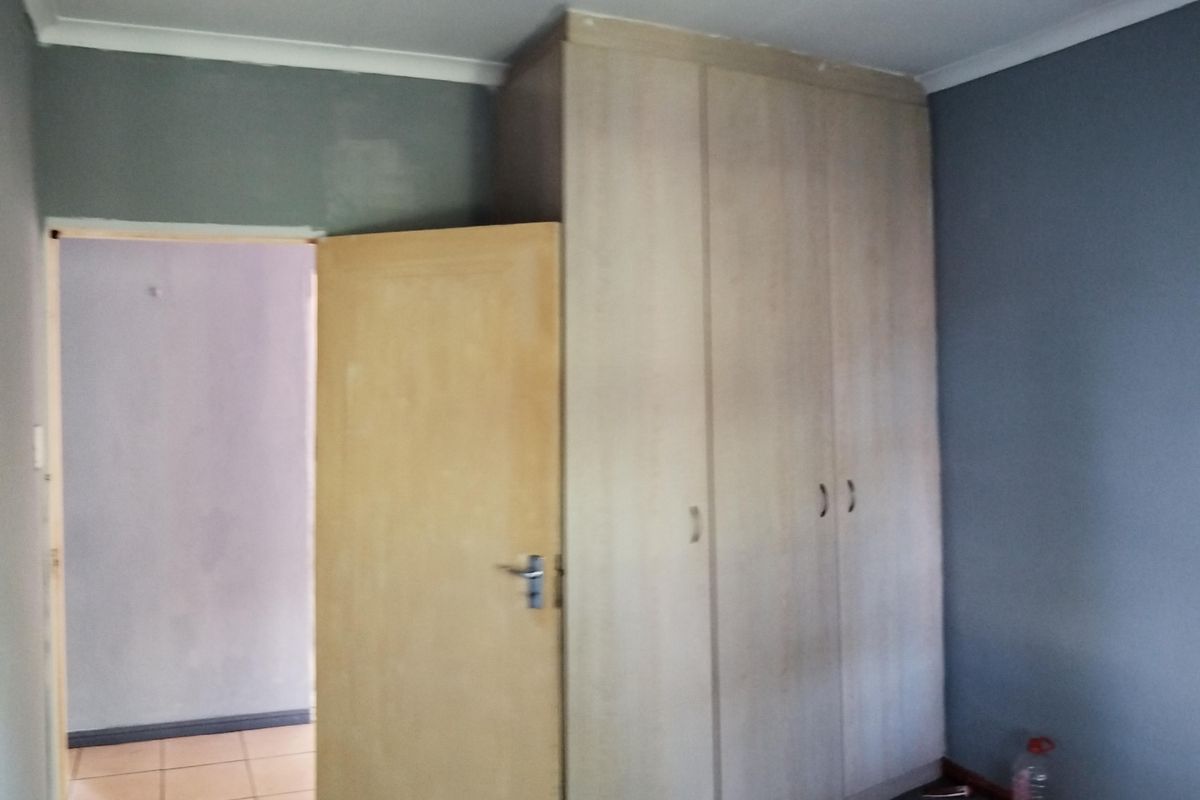 A bedroom featuring a built-in wardrobe and neutral wall tones, offering a blank canvas for potential interior updates.