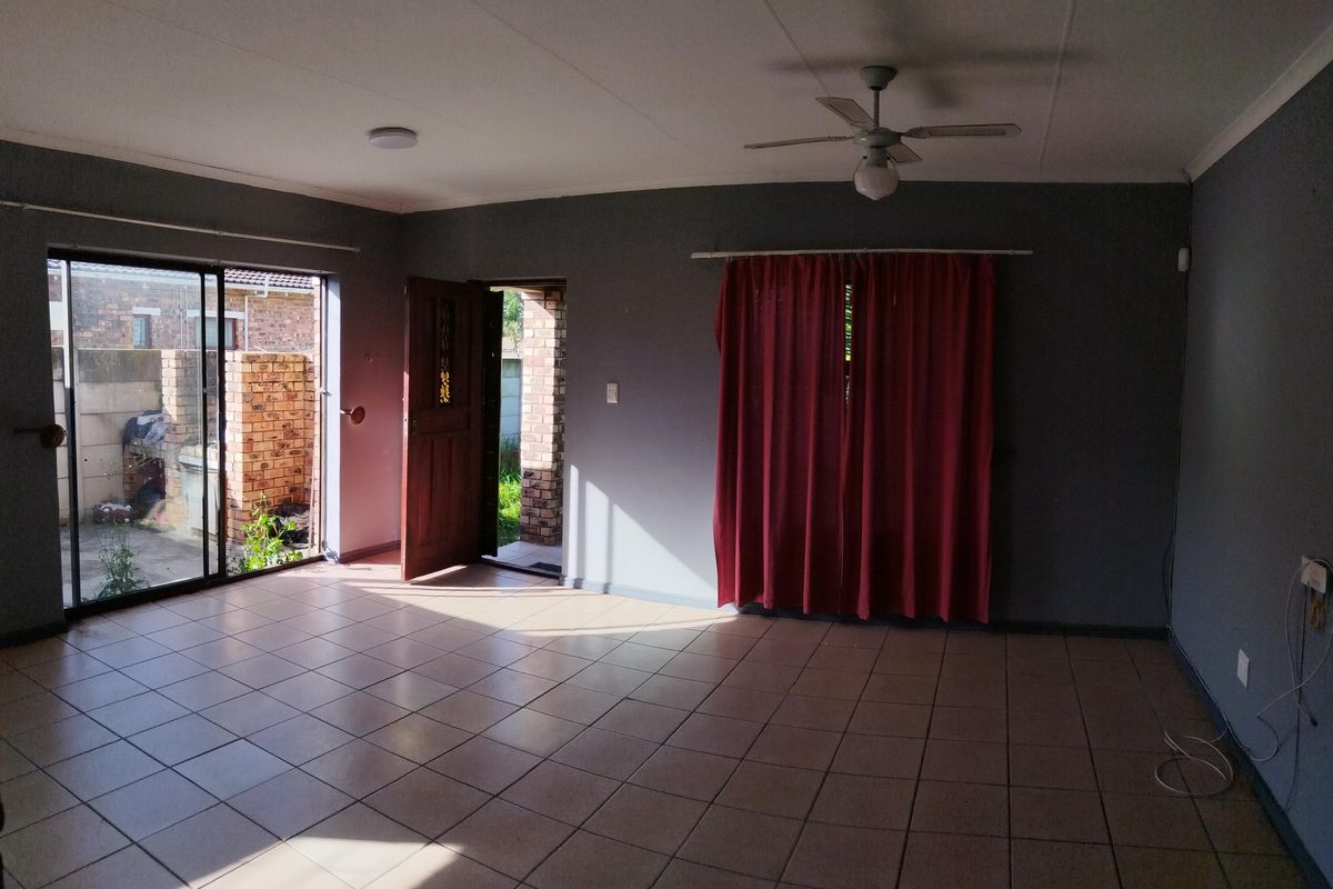 Spacious, empty living area featuring tiled flooring, a ceiling fan, and direct access to the exterior through a sliding glass door and timber entrance door.