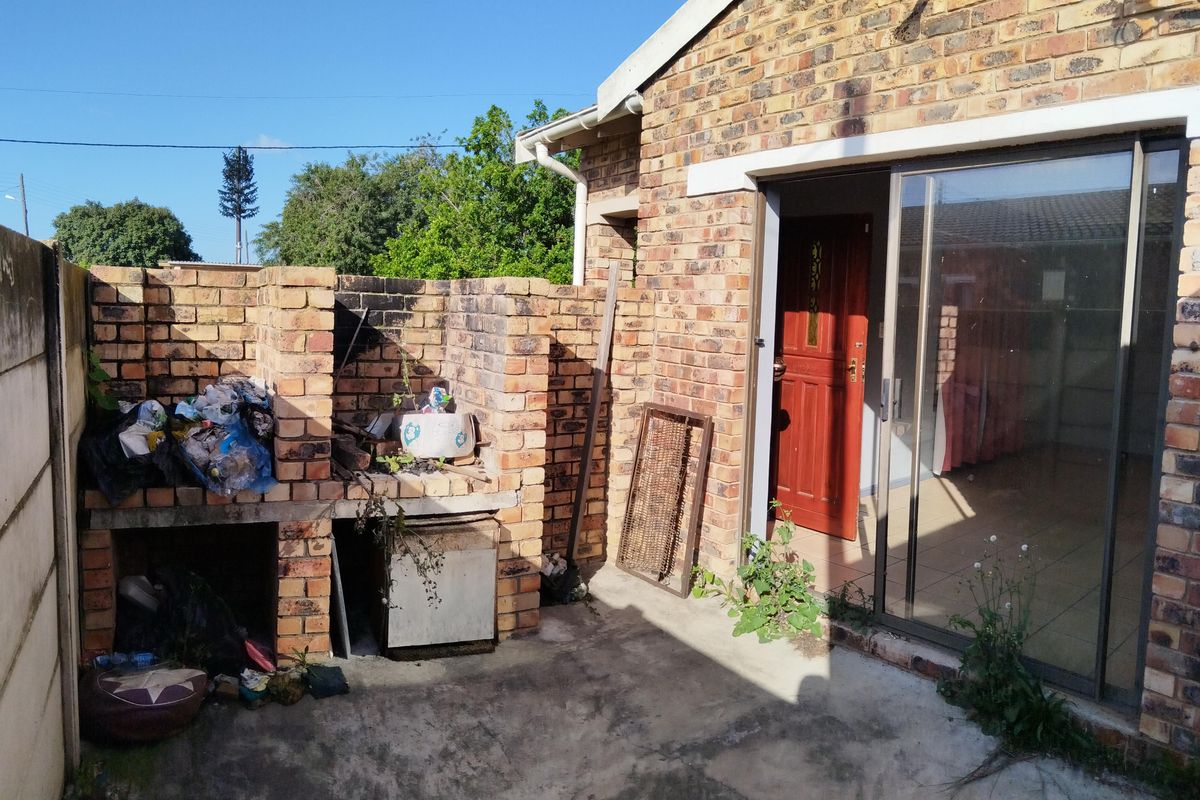 Rear exterior area featuring a brick braai, concrete patio, and sliding door access to the interior living space.