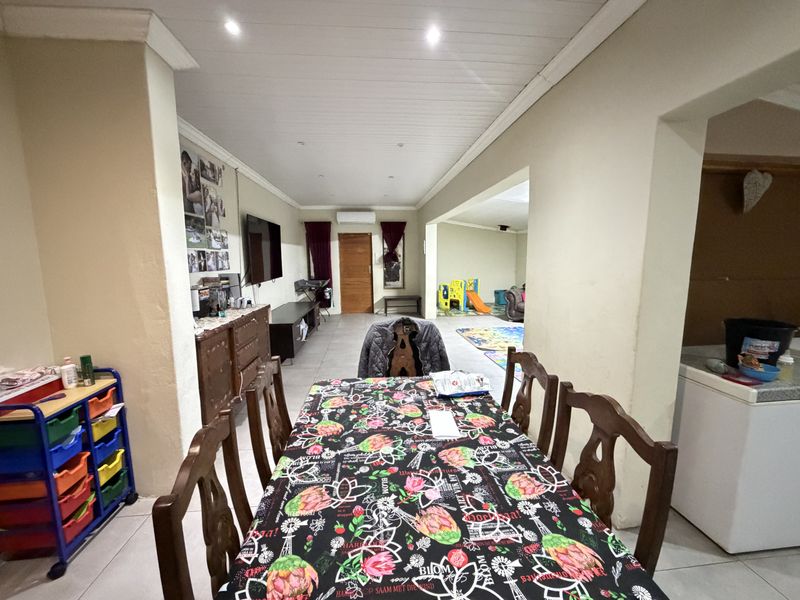 Spacious open-plan living and dining area featuring tiled flooring, recessed lighting, and a wall-mounted air conditioning unit.