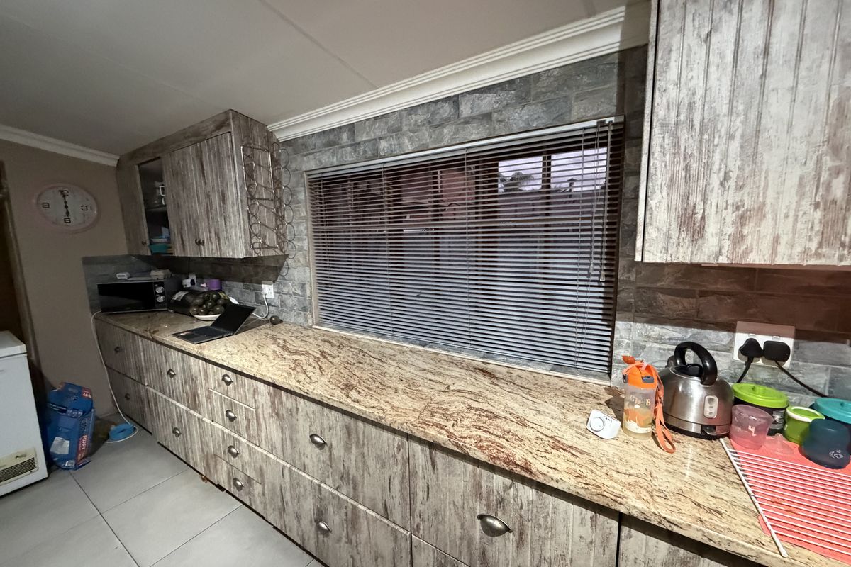 Kitchen area featuring granite countertops, stone-look wall cladding, and extensive built-in cabinetry with a rustic finish.
