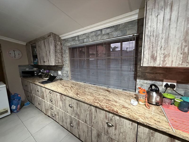Kitchen area featuring granite countertops, stone-look wall cladding, and extensive built-in cabinetry with a rustic finish.
