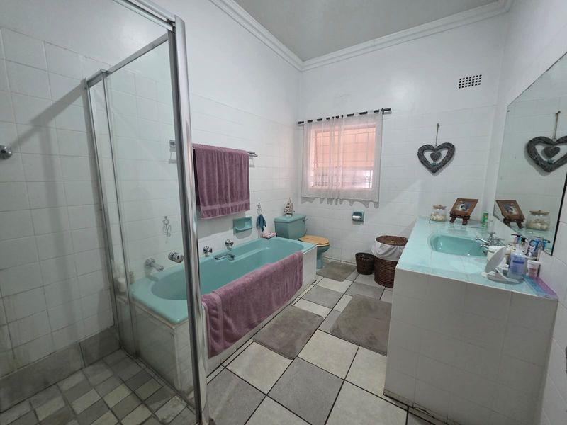 A dated bathroom featuring a built-in bathtub, separate glass shower enclosure, and a tiled vanity with an integrated sink.