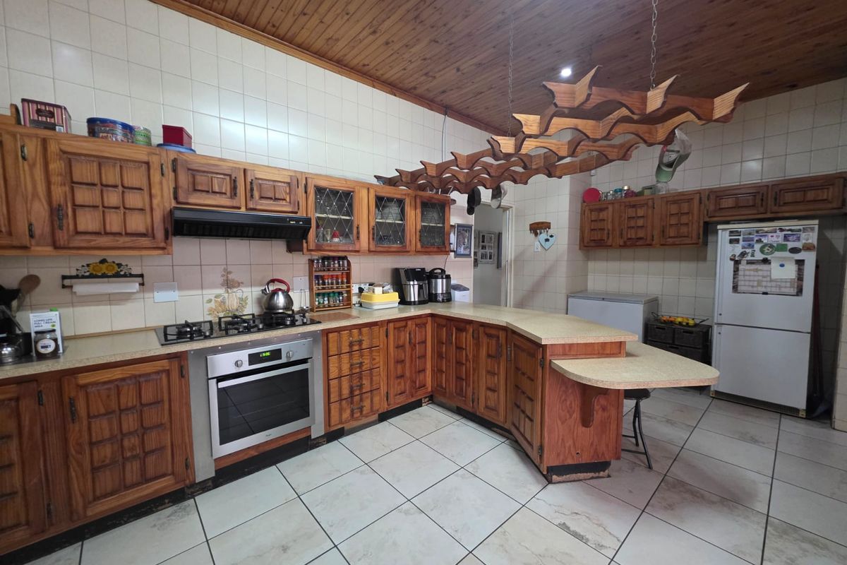 Spacious kitchen featuring traditional wooden cabinetry, built-in oven, gas hob, and tiled finishes, offering a functional layout with potential for modern updates.
