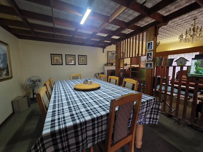 A dining room featuring a distinctive coffered timber ceiling and a decorative timber room divider, creating a traditional and enclosed atmosphere.