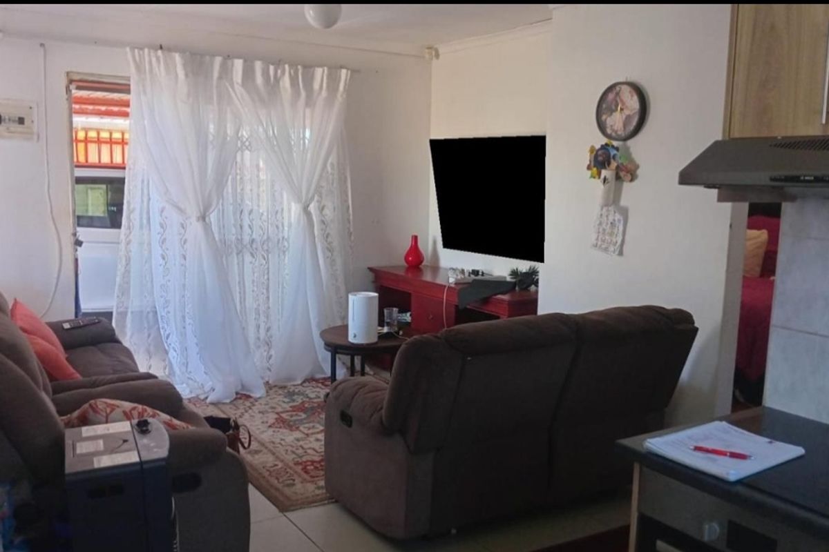 Open plan living area featuring tiled flooring and direct access to the exterior through a sliding door, adjacent to a compact kitchen space.