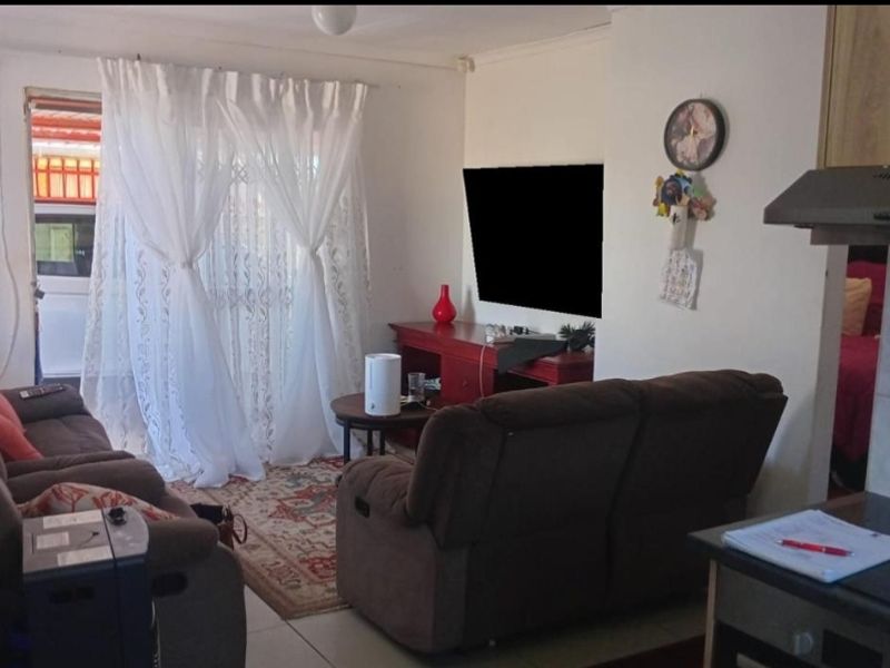 Open plan living area featuring tiled flooring and direct access to the exterior through a sliding door, adjacent to a compact kitchen space.