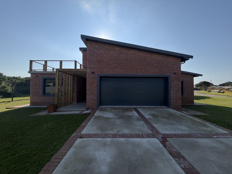 Modern single-story brick house featuring a double garage, concrete driveway, and an accessible rooftop terrace with timber pergola.