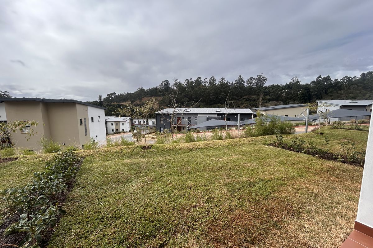 A view of the rear garden area overlooking the surrounding residential complex and hillside landscape.