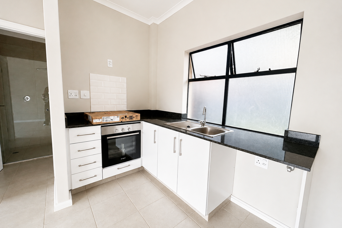 A clean, modern kitchen featuring white cabinetry, granite countertops, a built-in oven, and a tiled backsplash, offering a functional and bright workspace.
