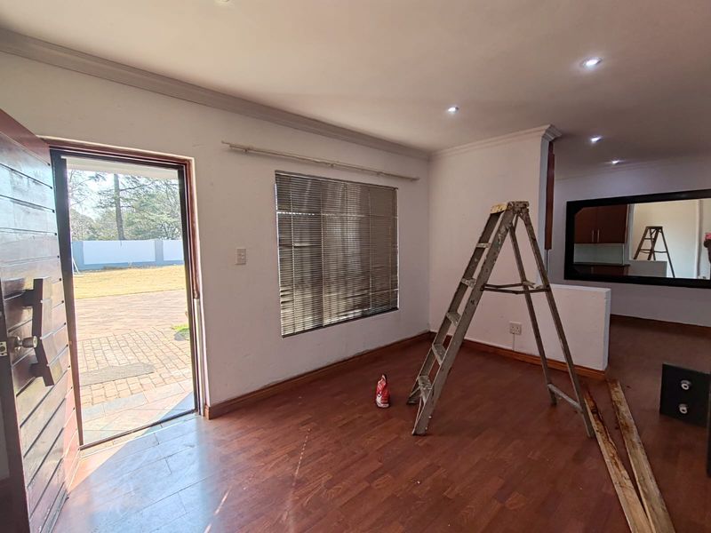 An open-plan living area featuring laminate flooring, recessed lighting, and direct access to the exterior, currently undergoing minor maintenance.