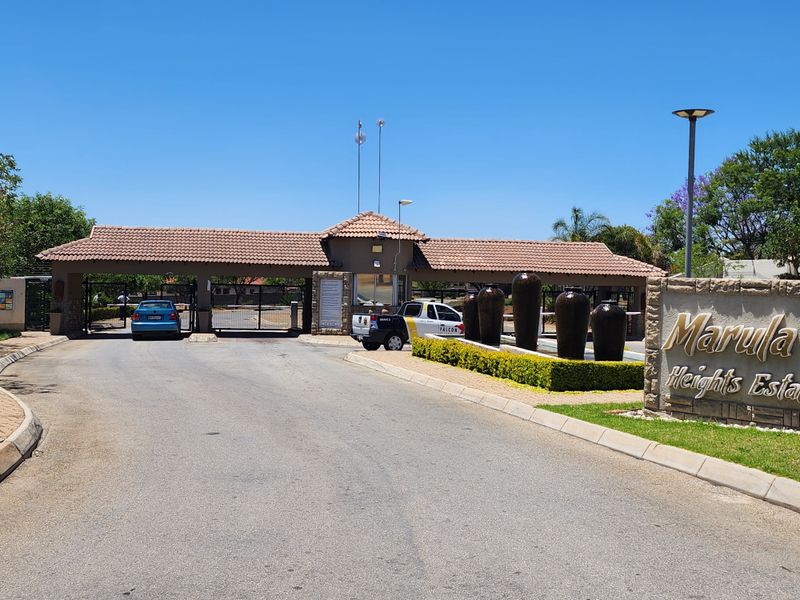 The main entrance gatehouse of Marula Heights Estate, featuring stone cladding, a tiled roof, and professional landscaping.