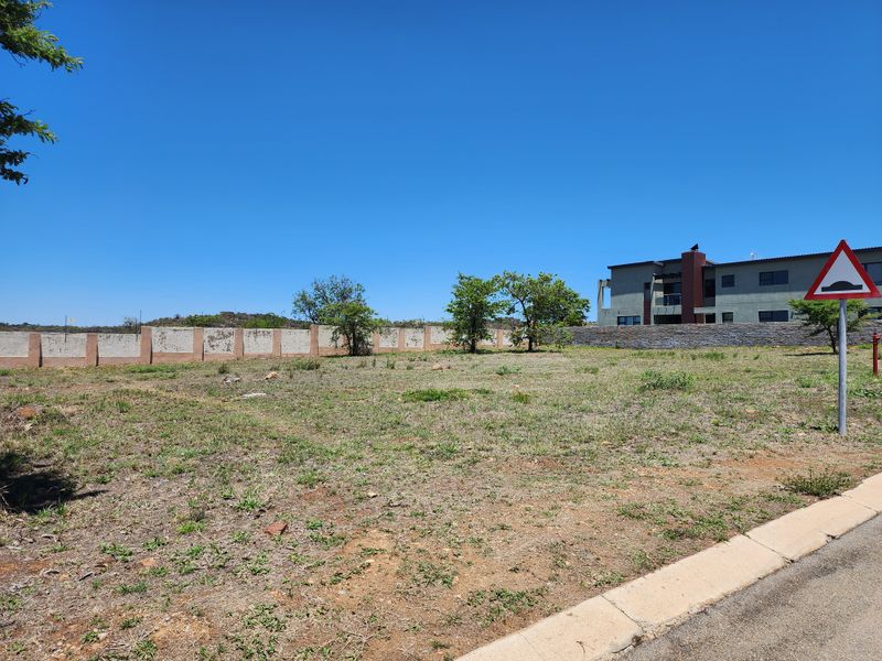 A vacant residential plot featuring a boundary wall and street-side curb, offering a clear space for potential development.