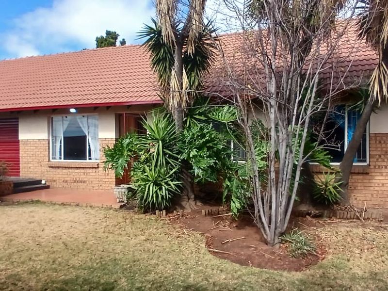 Front elevation of a townhouse featuring a tiled roof, facebrick exterior, and a double garage with red roller doors.