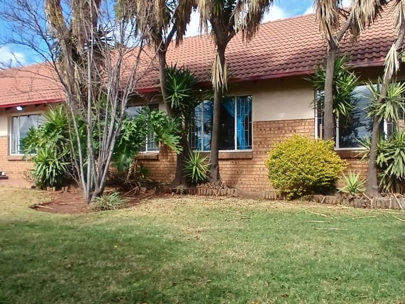 Front exterior view of a single-story townhouse featuring a tiled roof, brick facade, and double garage with roller doors, set behind a front lawn.