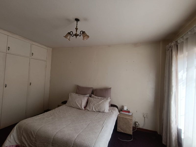 A bedroom featuring built-in cupboards and a ceiling light fixture, requiring cosmetic updates to the wall finishes.