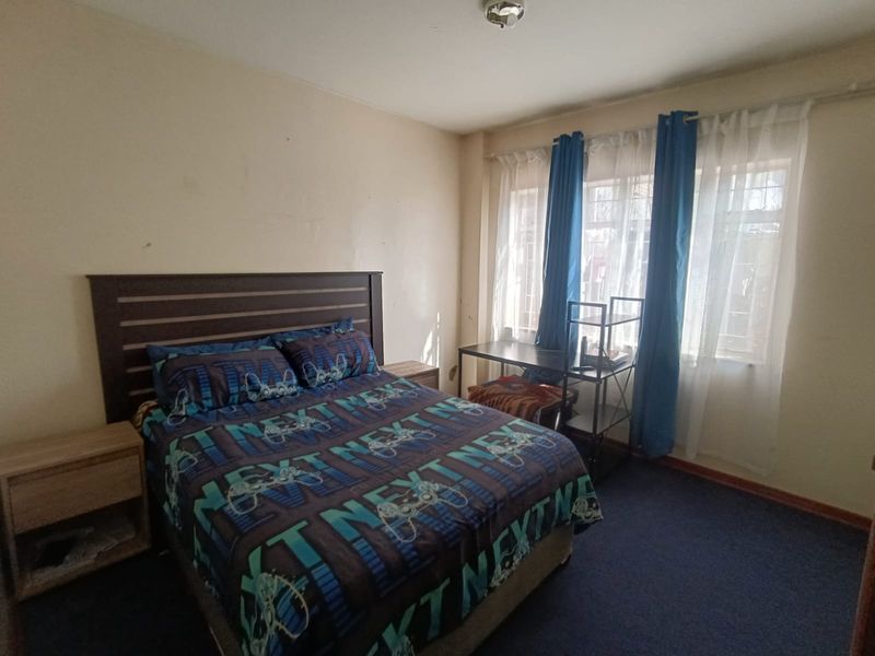 A functional bedroom featuring carpeted flooring and a window fitted with security bars, offering a neutral space ready for personalization.