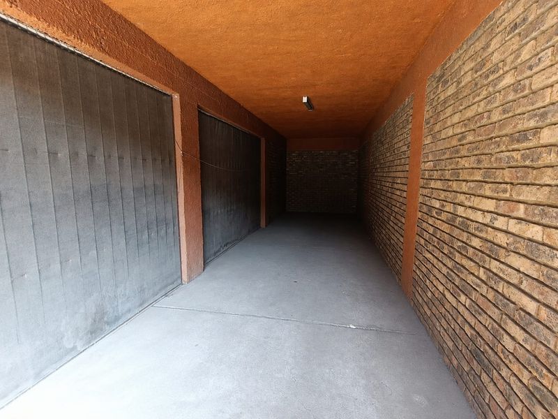 A spacious, empty garage featuring exposed brick walls, concrete flooring, and secure garage doors.