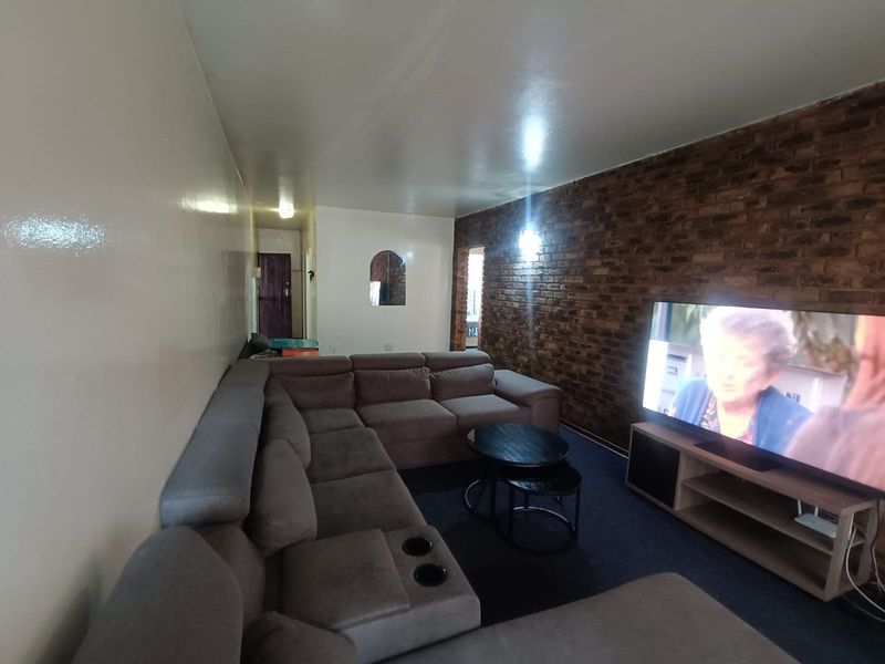 A living room featuring an exposed brick accent wall and an interior archway, providing a distinct character to the space.