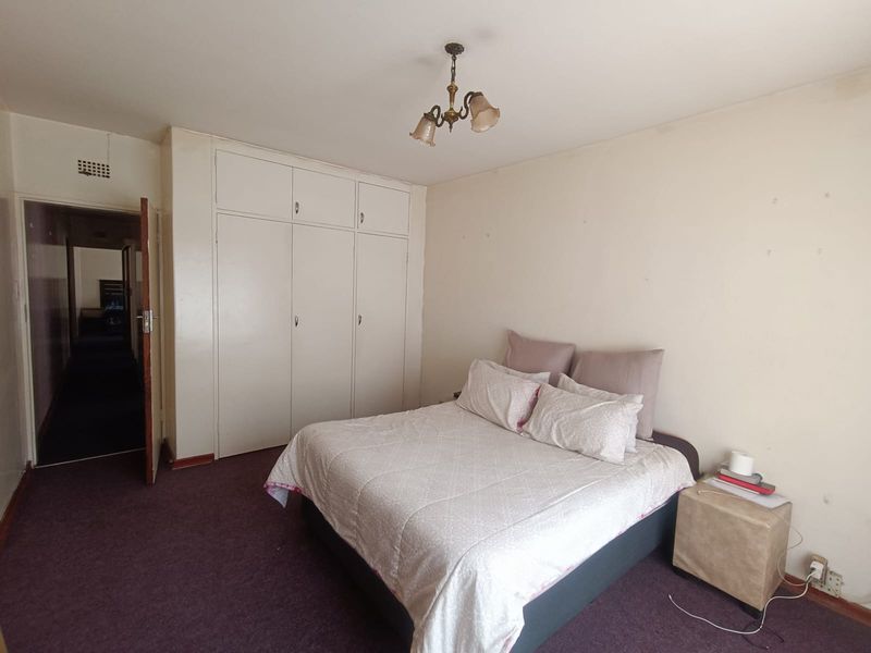 A bedroom featuring built-in cupboards, carpeted flooring, and a central light fixture, offering a functional space ready for cosmetic updates.