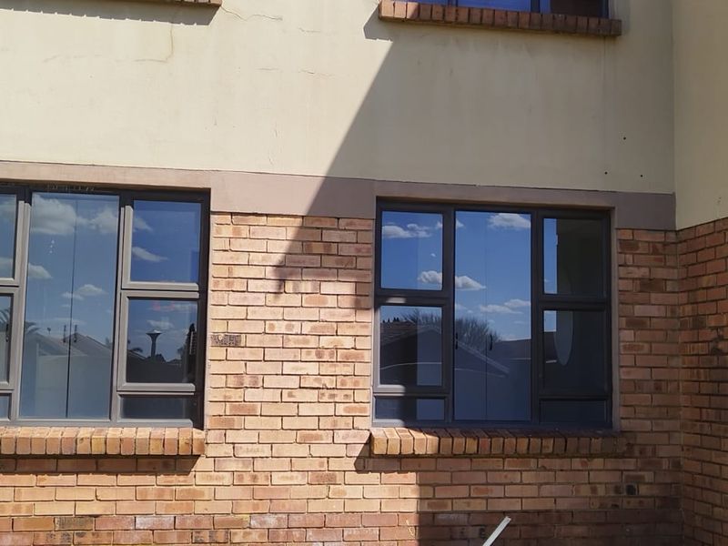 Front facade of the apartment building featuring face brick detailing, aluminium window frames, and visible exterior plaster cracking.