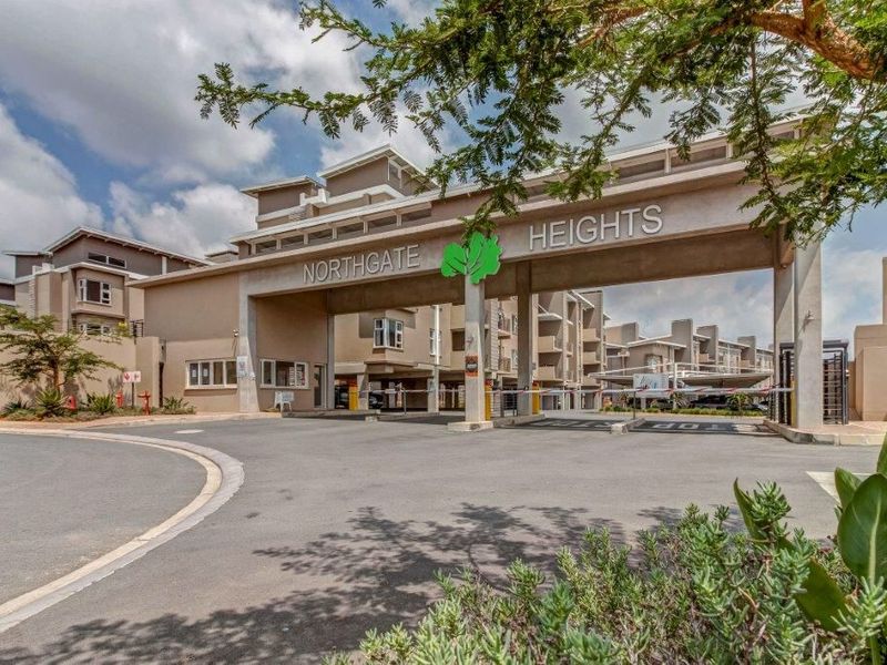 The main entrance and security gatehouse of the Northgate Heights townhouse complex, featuring a paved driveway and controlled access boom gates.