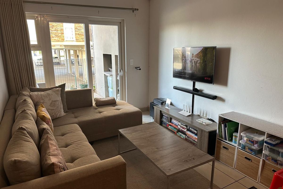 A comfortable living room featuring tiled flooring and a large sliding glass door that provides natural light and access to the exterior.