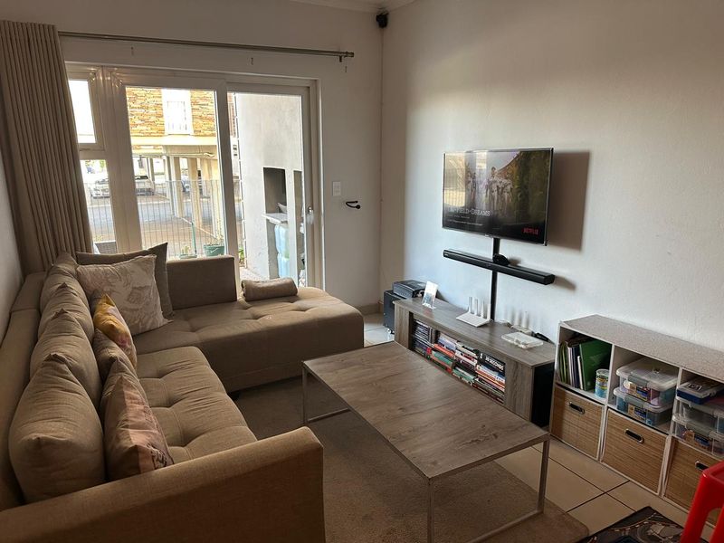 A comfortable living room featuring tiled flooring and a large sliding glass door that provides natural light and access to the exterior.