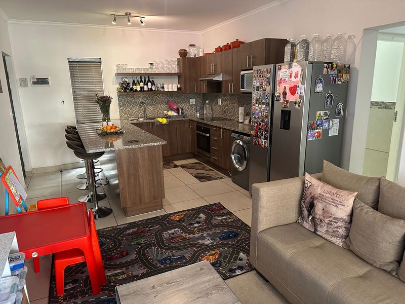 Open-plan kitchen and living area featuring granite countertops, built-in cabinetry, and a breakfast bar, creating a functional and connected space for daily living.