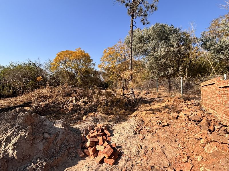 A large, undeveloped garden area featuring a brick boundary wall and wire fencing, currently requiring significant landscaping and site clearing.