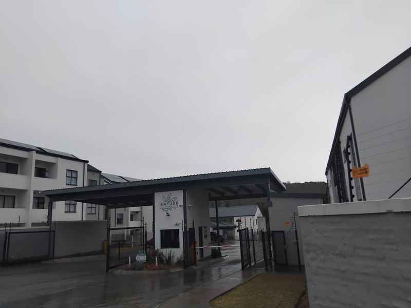 The entrance to Safubi Views apartment complex, featuring a secure gatehouse, boom gate access, electric fencing, and modern apartment buildings with solar panels.