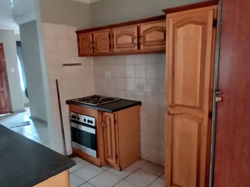 A functional kitchen featuring built-in wooden cabinetry, an integrated oven and hob, tiled backsplash, and durable countertops, offering a practical layout for daily use.
