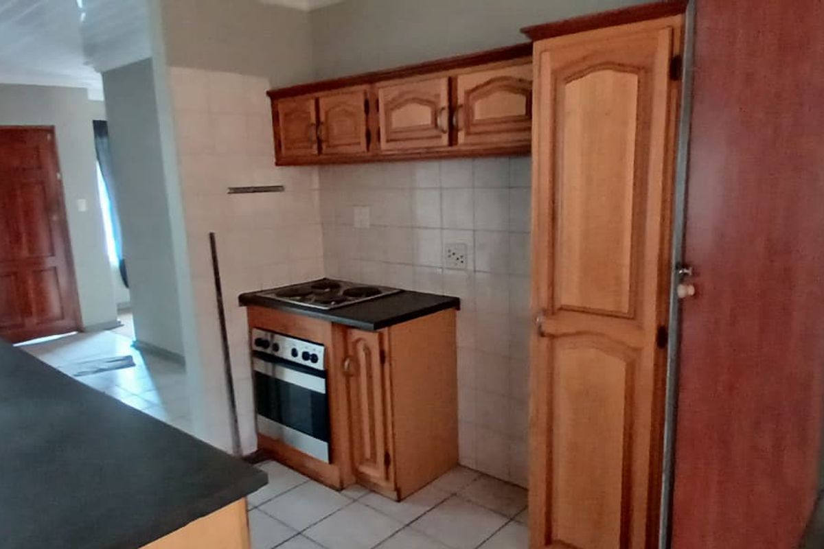 A functional kitchen featuring built-in wooden cabinetry, an integrated oven and hob, tiled backsplash, and durable countertops, offering a practical layout for daily use.
