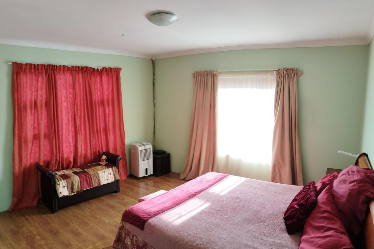 A spacious bedroom featuring laminate flooring and natural light, providing a comfortable and functional living space.