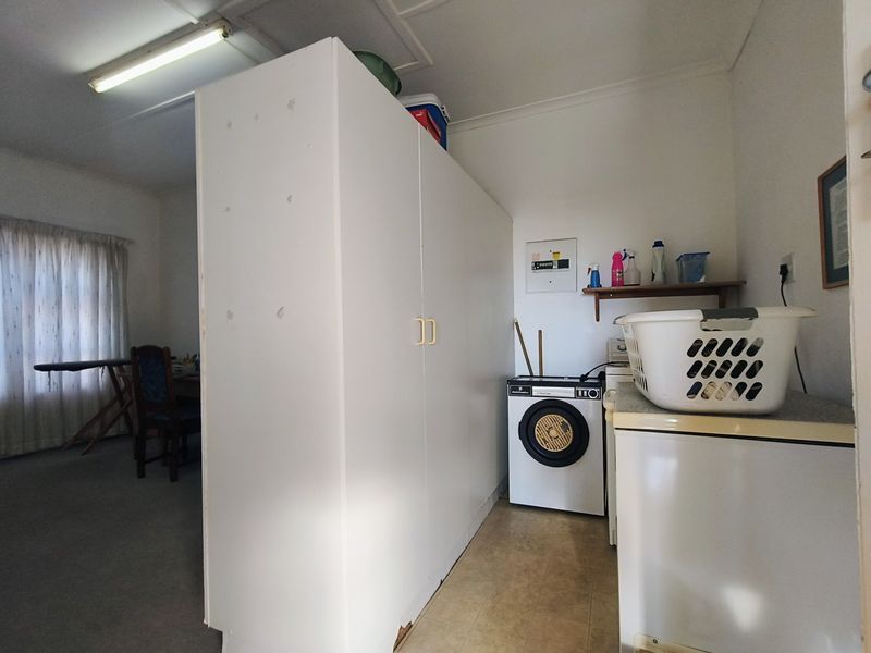 A functional laundry area featuring built-in cabinetry, tiled flooring, and an integrated electrical distribution board, providing practical utility space.