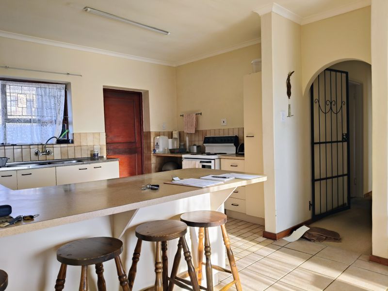 A functional kitchen featuring laminate countertops, tiled backsplash, and a breakfast bar, leading through an arched doorway to the rest of the home.