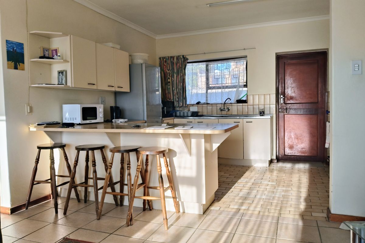 A functional kitchen featuring built-in cabinetry, a breakfast bar, tiled flooring, and a tiled backsplash, offering a practical layout with natural light.