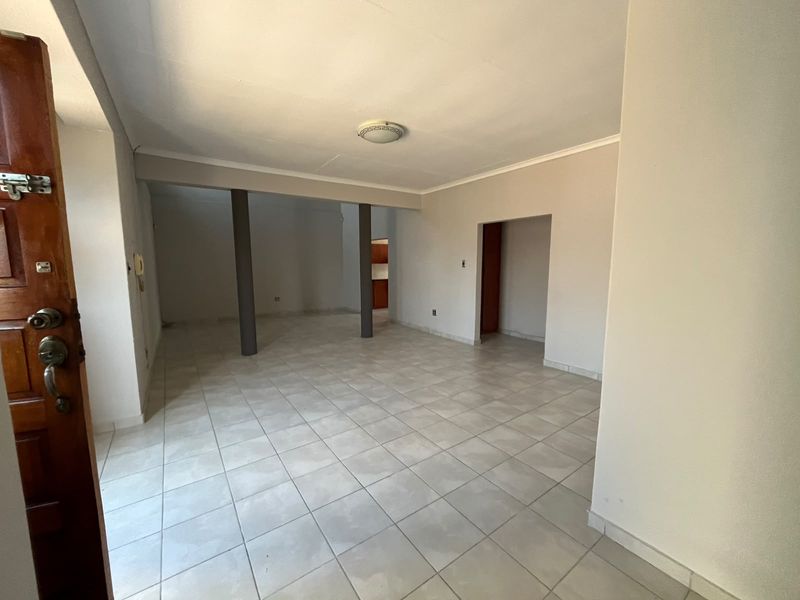 An open-plan living area featuring neutral tiled flooring, structural support columns, and a clean, minimalist aesthetic ready for furnishing.
