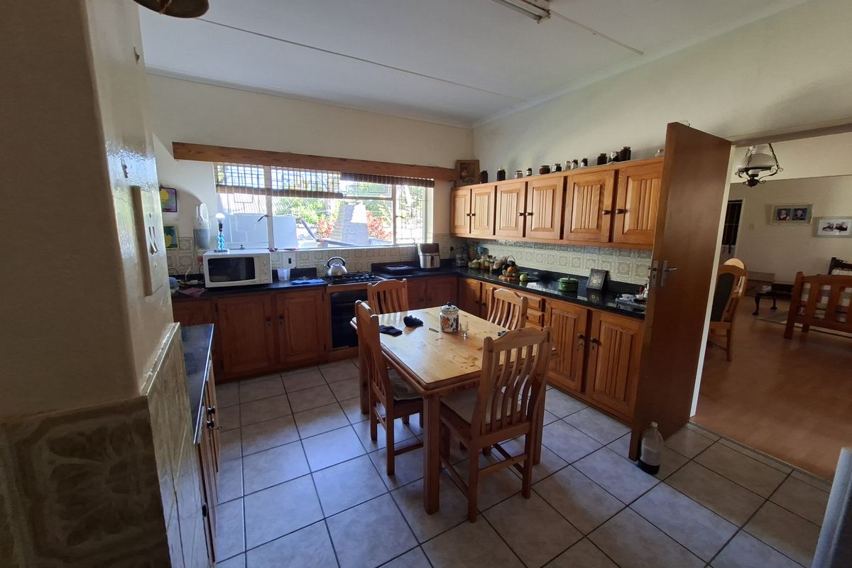A functional kitchen featuring traditional wooden cabinetry, stone countertops, tiled backsplash, and tiled flooring, offering a classic and practical layout.