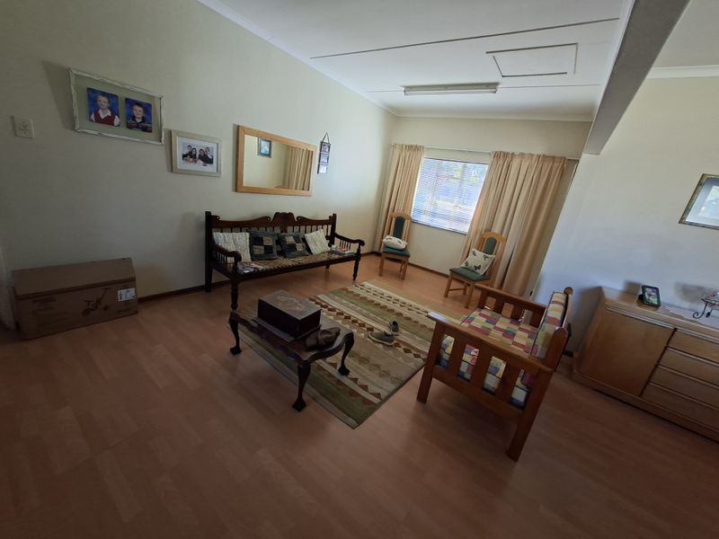 A living room featuring laminate flooring and neutral wall finishes, offering a functional space with natural light from the window.