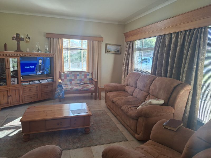 A comfortable living room featuring tiled flooring, timber window pelmets, and large windows that provide natural light.