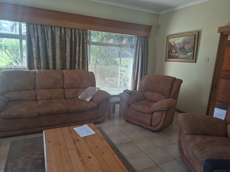 A living room featuring tiled flooring and a large window with a timber pelmet, offering a functional and traditional living space.