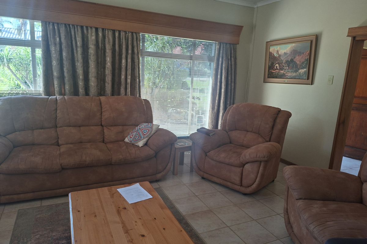 A living room featuring tiled flooring and a large window with a timber pelmet, offering a functional and traditional living space.
